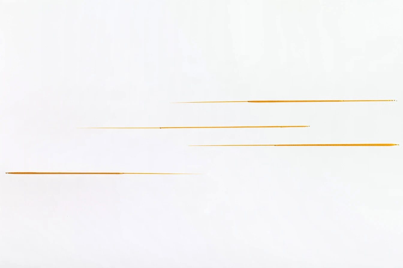 Four long mustard-yellow stitches across white paper